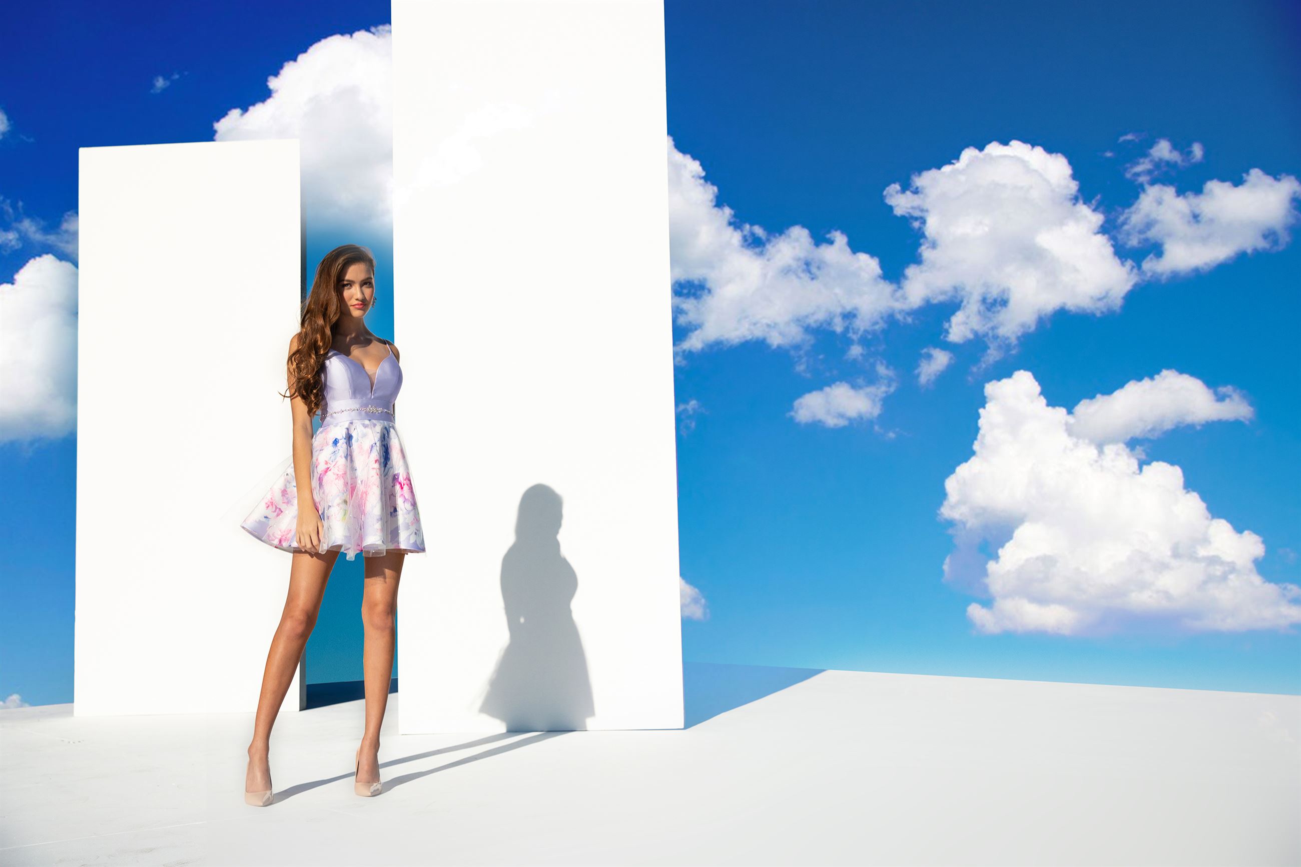 Brunette model in short purple dress in front of clouds